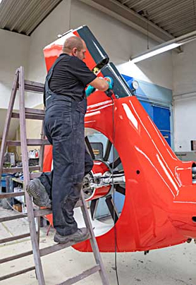 Arbeiter auf einer Leiter lackiert ein großes Hubschrauberteil