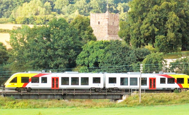 Die Vogelsbergbahn fährt gerade vor der Burgruine Angersbach vorbei