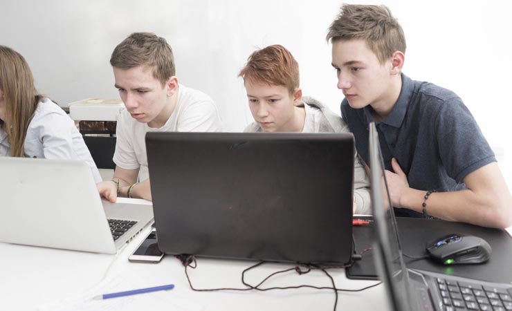 Drei Jungen sitzen vor ihren Computern